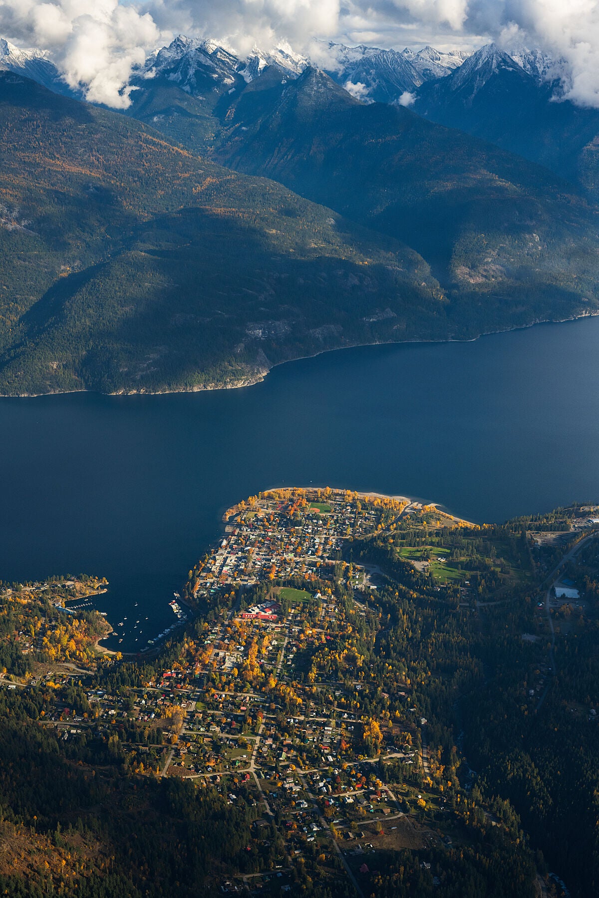 A fall view of Kaslo, British Columbia with the towering Purcell Mountains in the background, looking out over the town and surrounding area, fine art print by Ashley Voykin