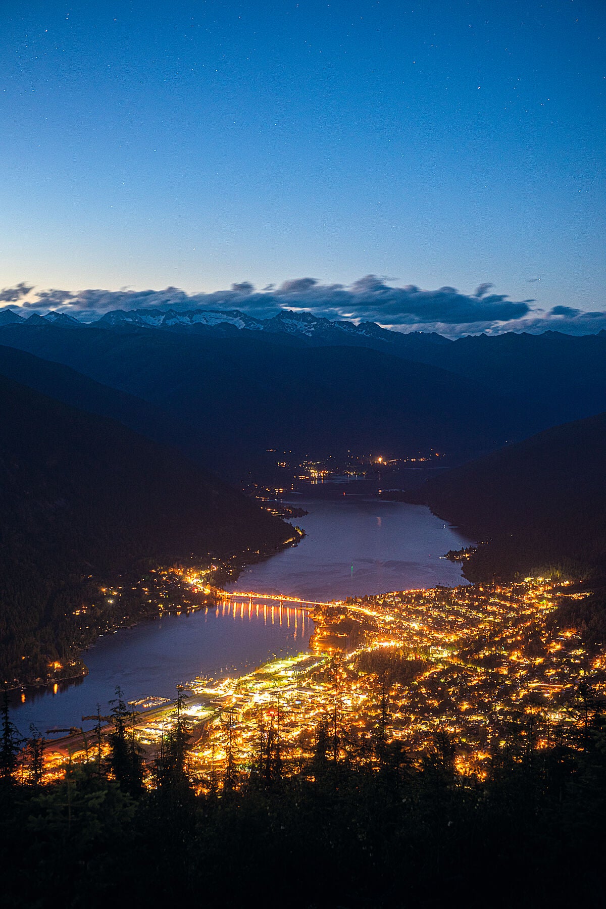 The lights of Nelson, British Columbia, glowing in the evening light, landscape photography by Ashley Voykin.