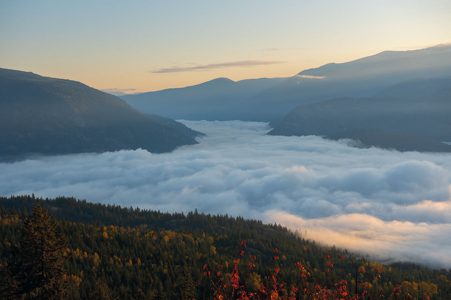 A fall sunrise above the valley fog covering Castlegar, in the Columbia Basin of British Columbia, local landscape photography by Ashley Voykin.