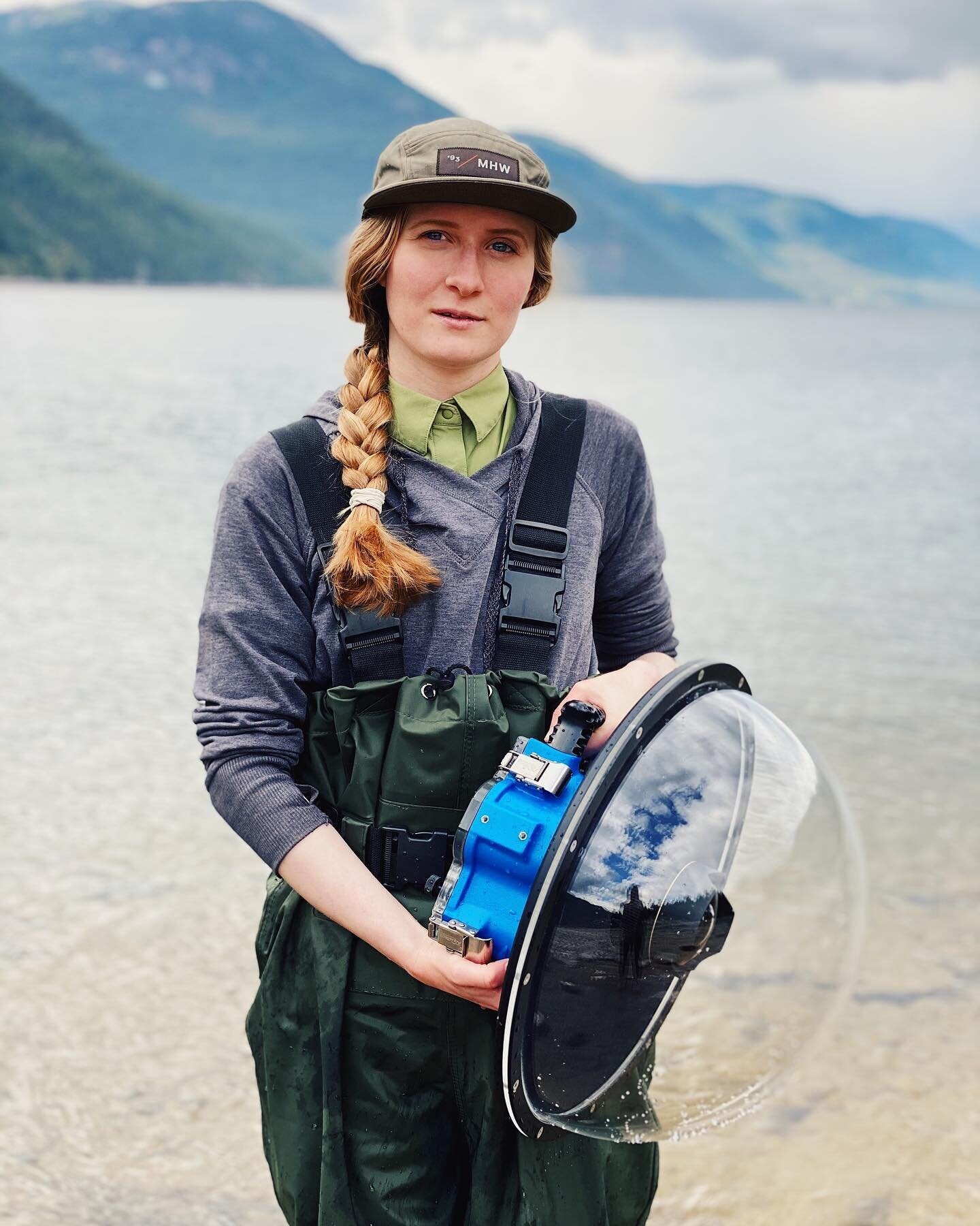 Ashley Voykin, a landscape photographer from Castlegar, British Columbia. Holding a camera within an underwater housing next to Lower Arrow Lake, in the Kootenay Region of British Columbia.