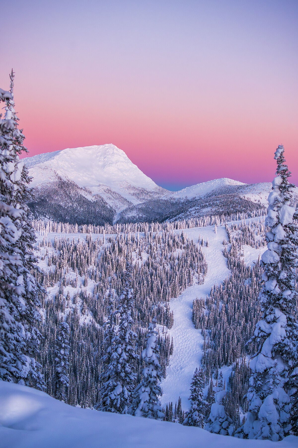 A scenic view of Old Glory, and the Rossland Range during a winter sunrise, with snow-covered trees and slopes, fine art landscape print by Ashley Voykin