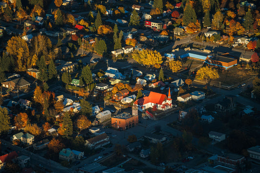 An aerial view of Rossland, BC, with a colorful autumn backdrop, showcasing the town's streets and surrounding area, fine art photograph by Ashley Voykin