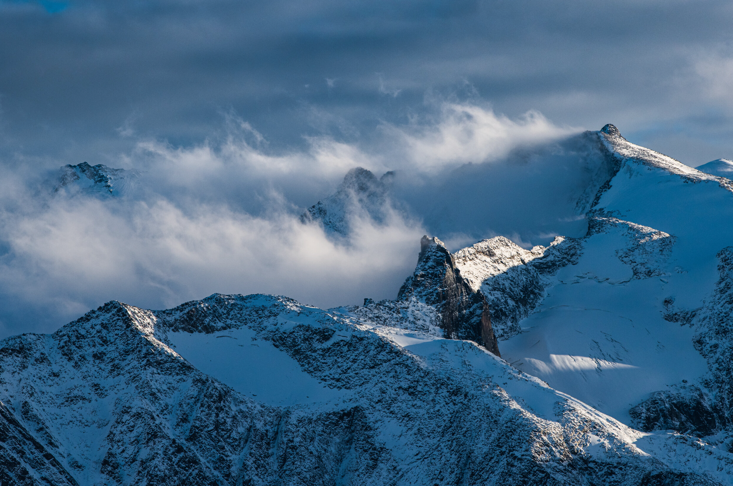 Fresh snow and storm clouds surrounding the mountain peaks of the Purcell Range, in the Kootenay region of BC.