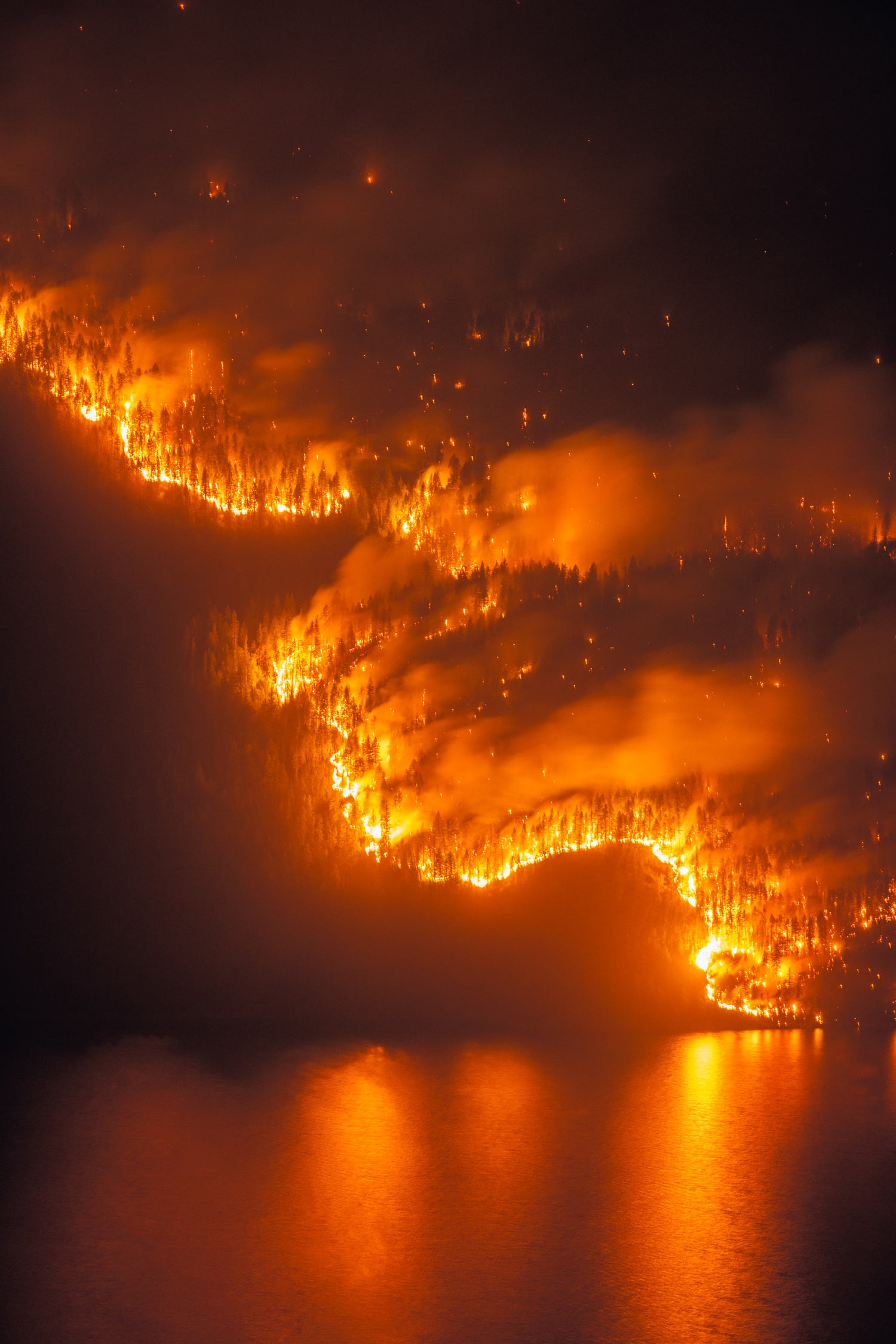 Night time view of Michaud Creek Wildfire burning above Lower Arrow Lake, near Castlegar, British Columbia. A location in the West Kootenay region.