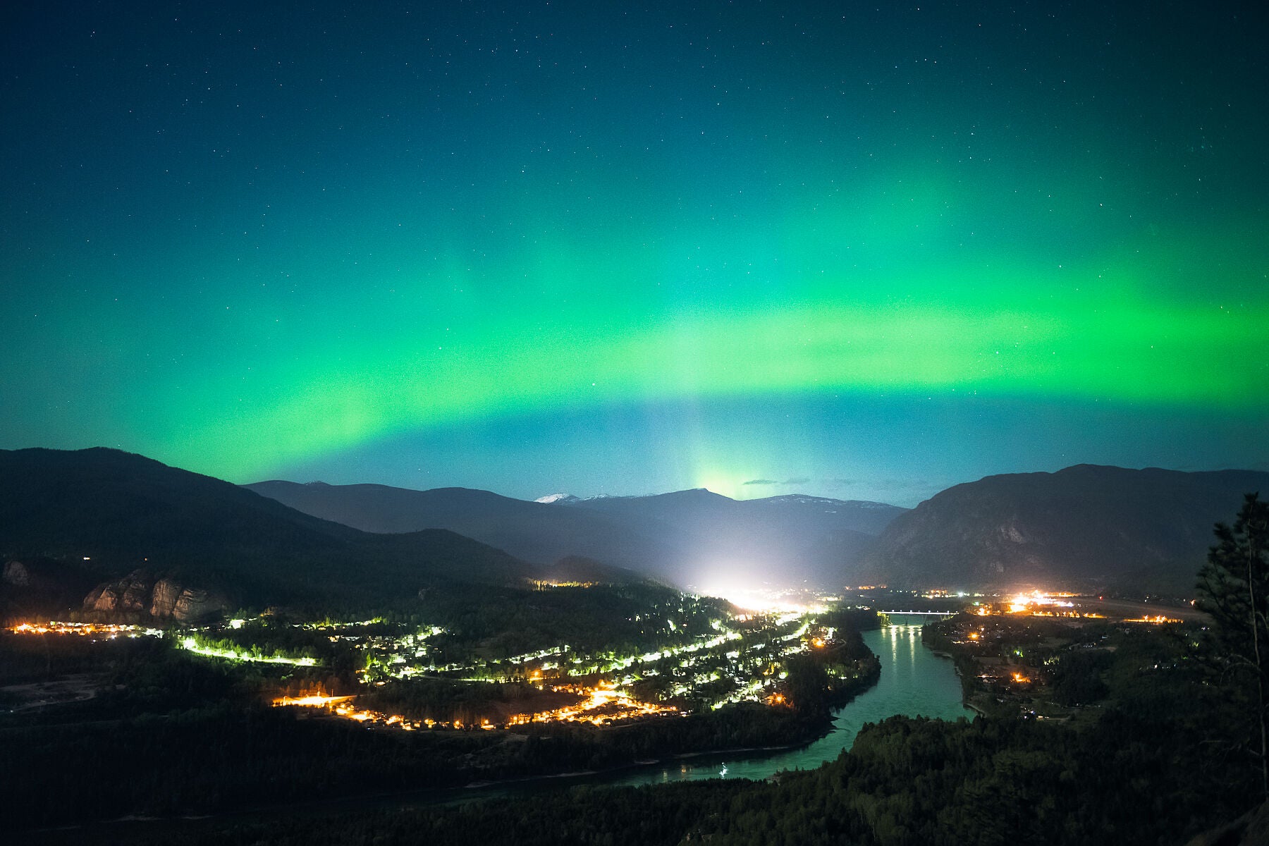Aurora Borealis dancing above the lights of Castlegar, and the Columbia River, West Kootenay landscape photography by Ashley Voykin