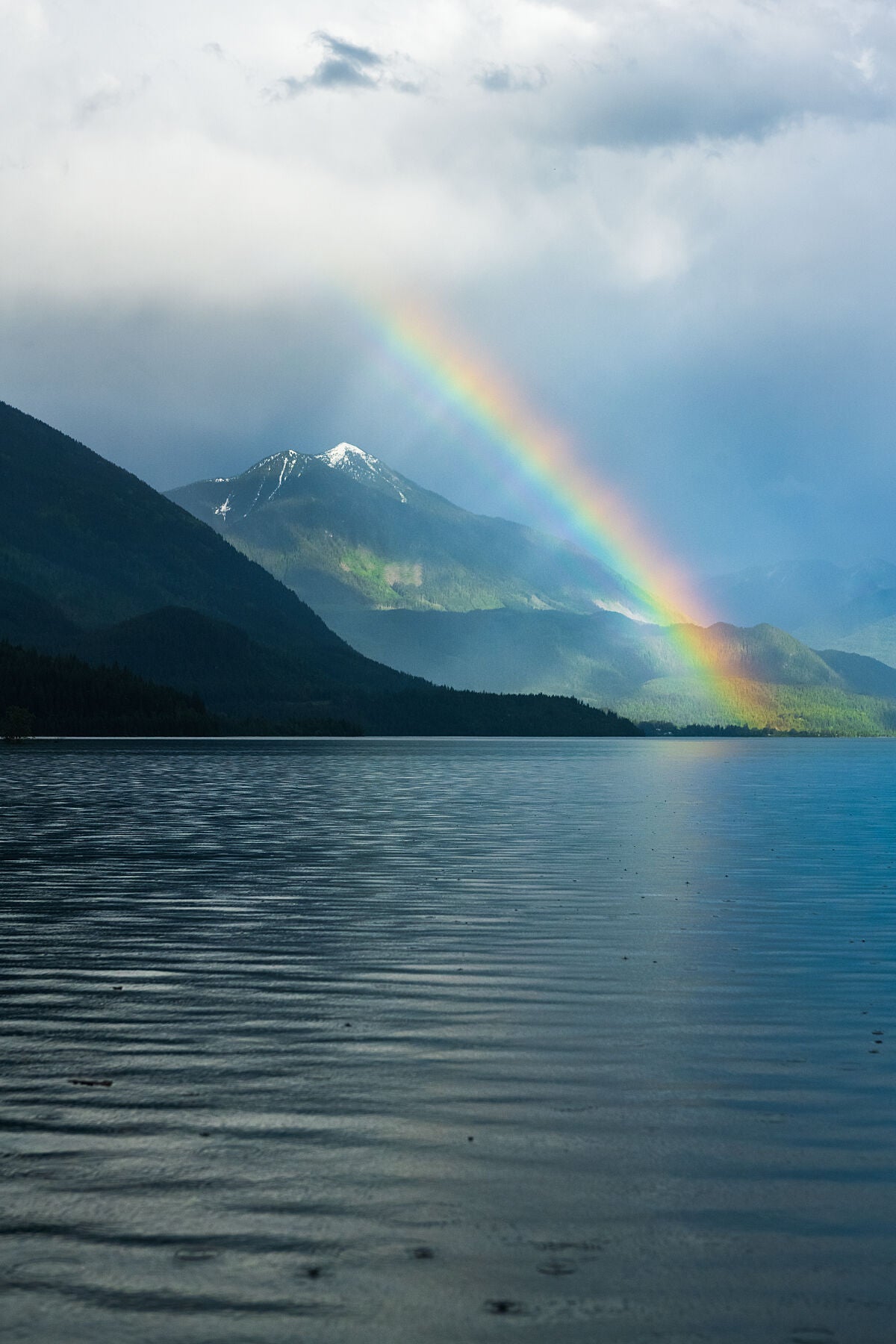 A rainbow over Idaho Peak and Slocan Lake, in the Slocan Valley of British Columbia. Landscape photography by Ashley Voykin.