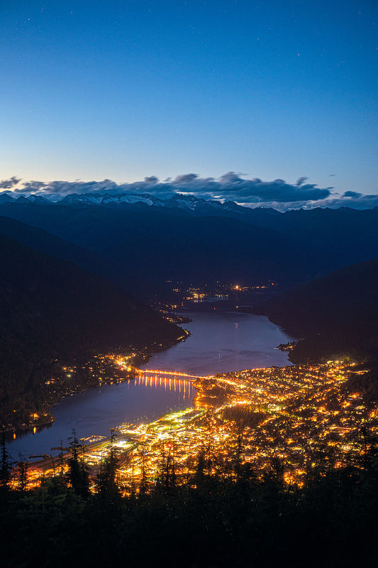 The lights of Nelson, British Columbia, glowing in the evening light, landscape photography by Ashley Voykin.