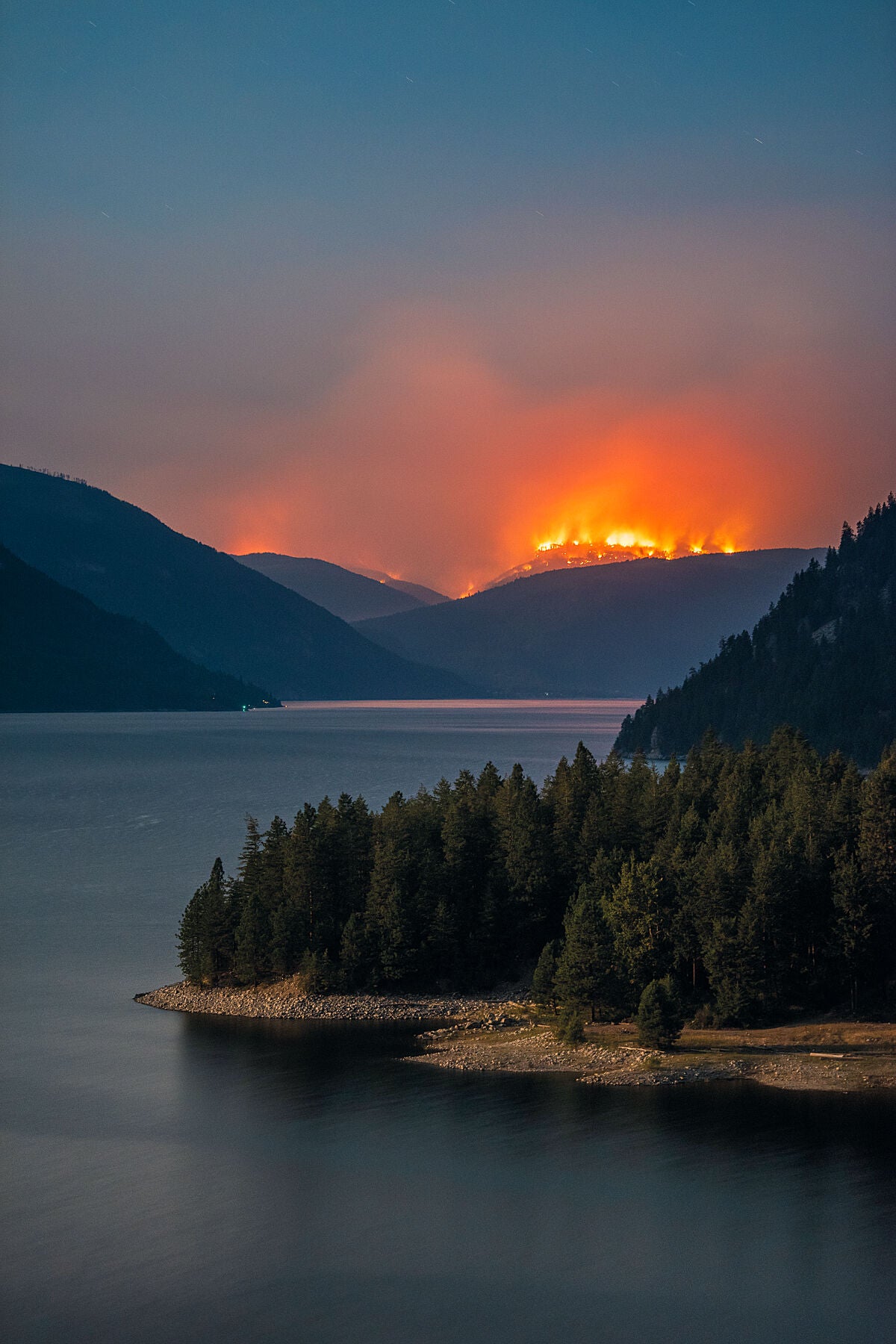 A view of the Renata Creek Wildfire across the water from Lower Arrow Lake, part of the Syringa Complex of fires. Environmental fine art landscape photo by Ashley Voykin.