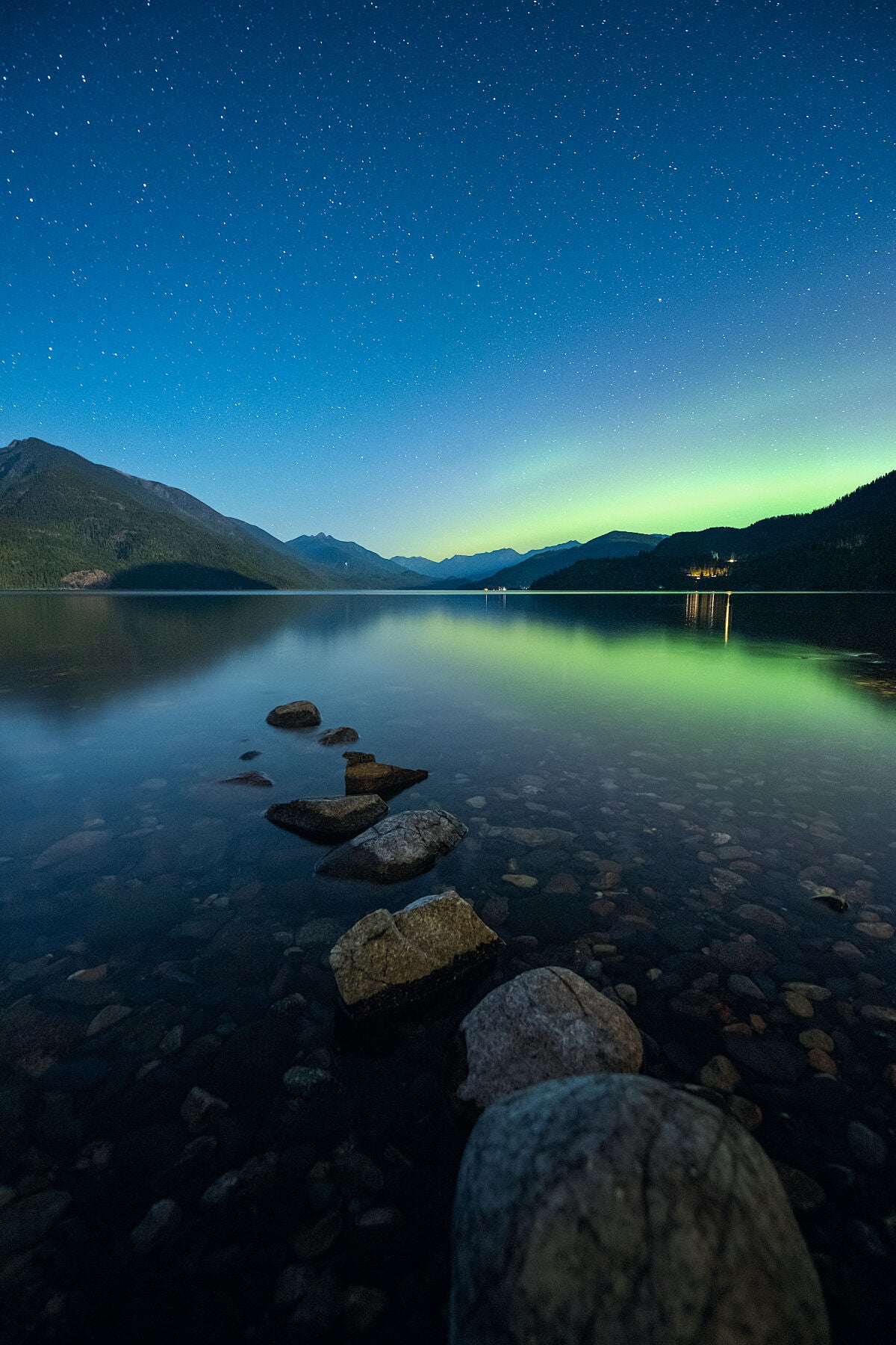 Faint Aurora Borealis dancing above Slocan Lake, in New Denver British Columbia. Fine art landscape photograph by Ashley Voykin.