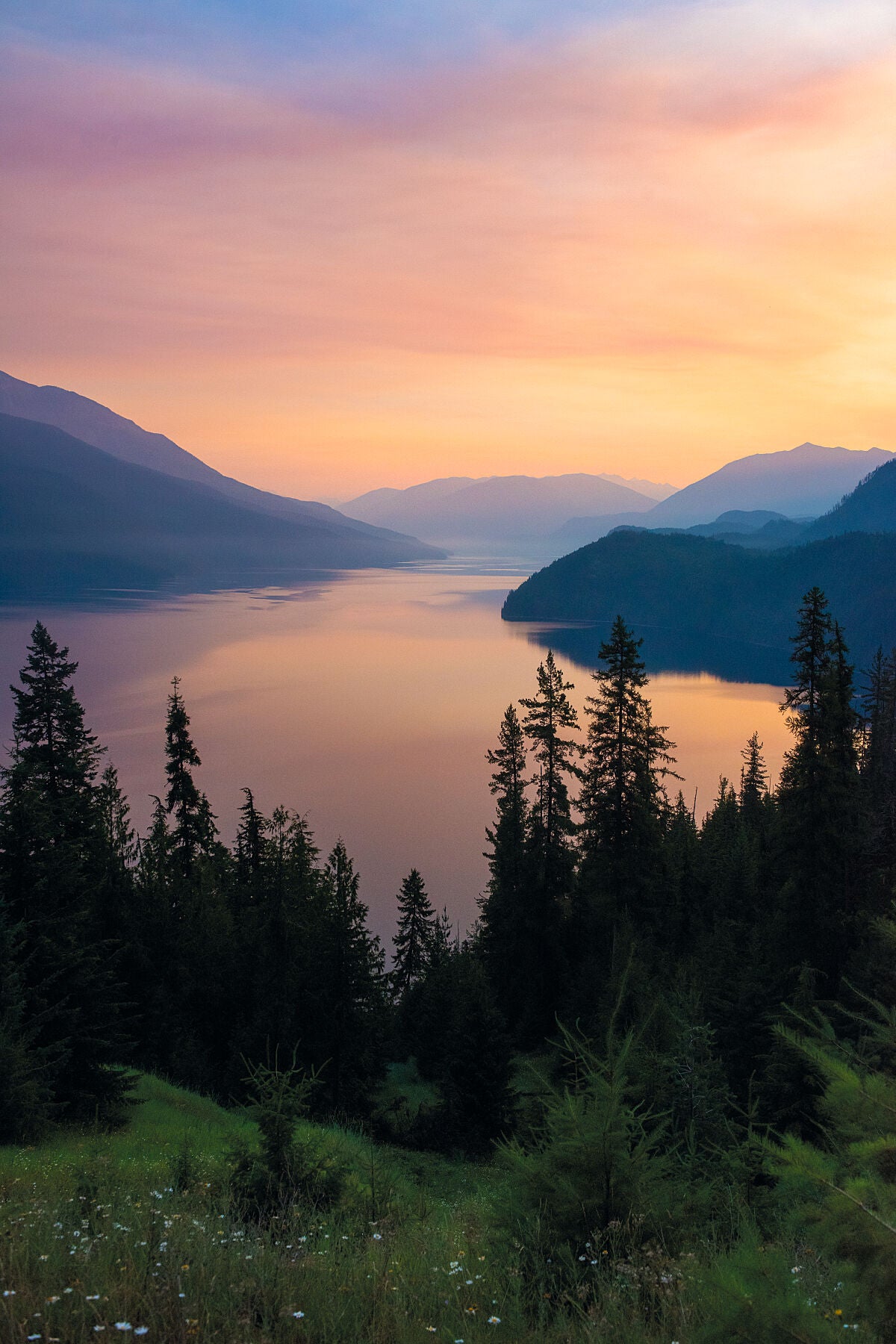 Wildfire smoke creates a vivid sunrise sky above Slocan Lake, in the West Kootenay region of British Columbia, Landscape photography by Ashley Voykin.